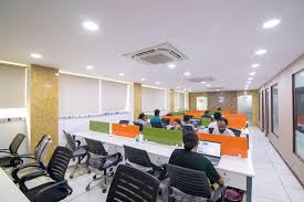 “Professionals working on laptops in a modern coworking space in Noida with open desks and creative interiors.”